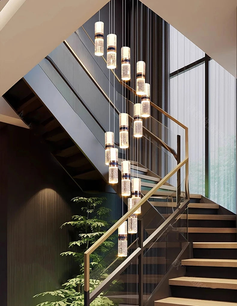 Modern crystal pendant lights illuminate a sleek staircase with glass railings and warm wood steps.