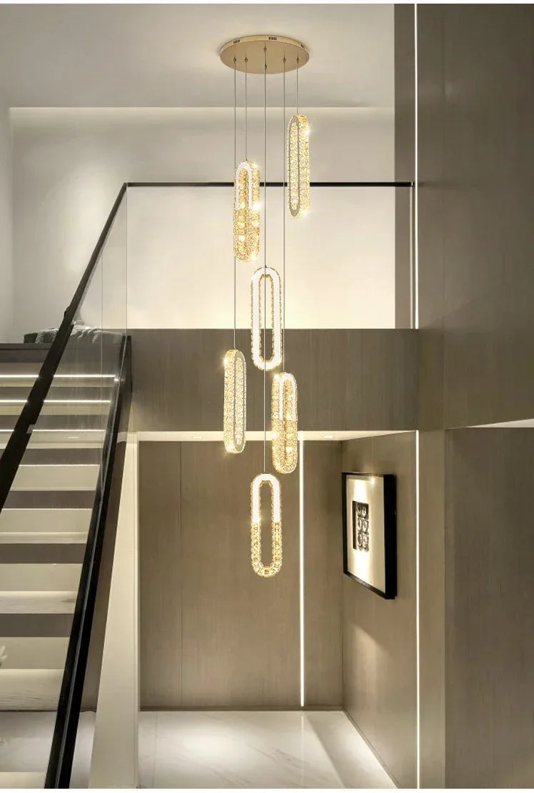 Modern crystal pendant lights with oval fixtures illuminating a minimalist staircase and hallway interior