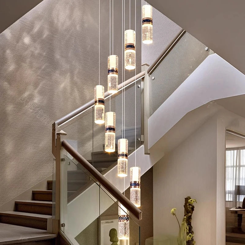 Modern crystal pendant lights illuminate a contemporary staircase with glass railings and warm ambient glow.
