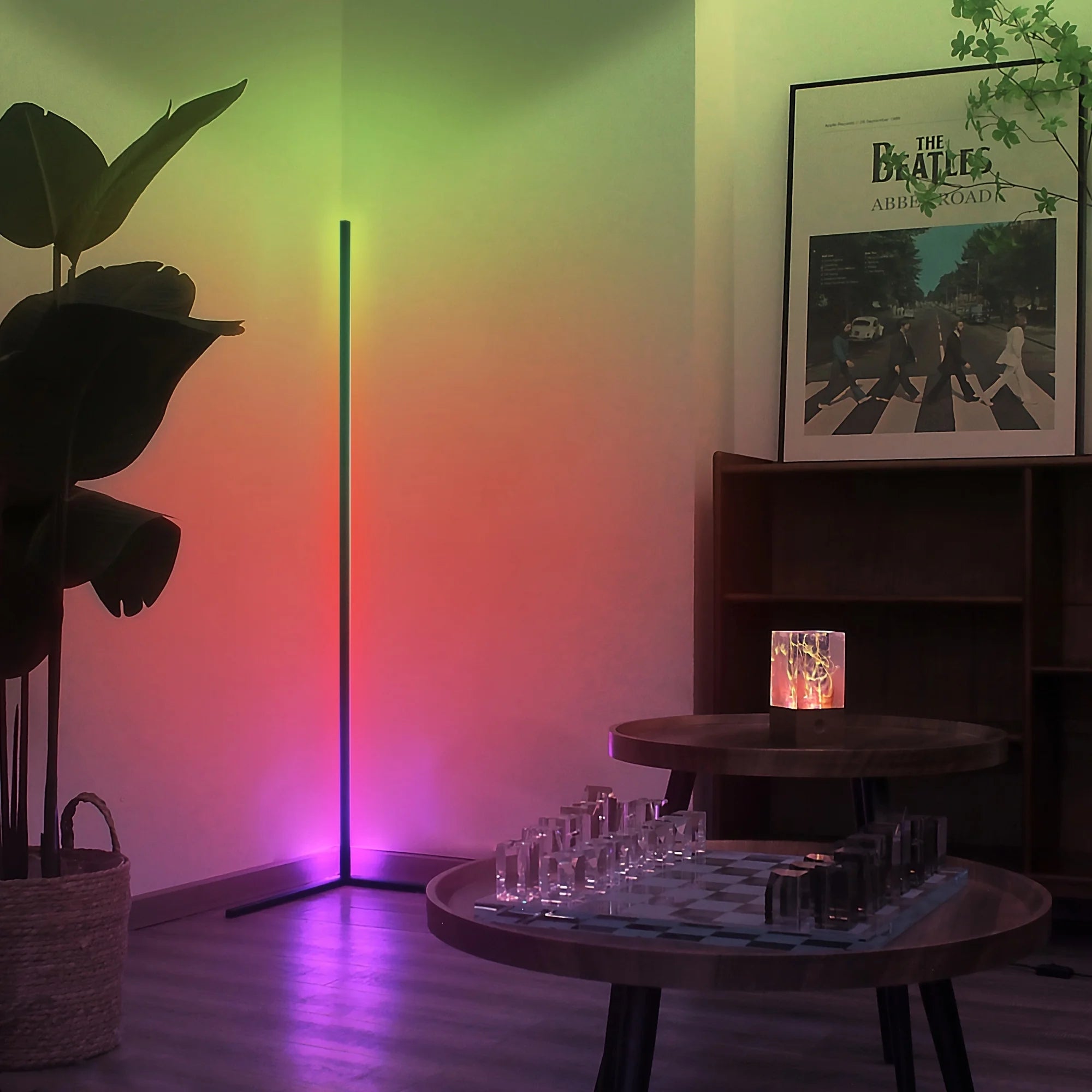 Room interior with a standing lamp casting colorful light, a framed poster on the wall, and a small table with decorative items.