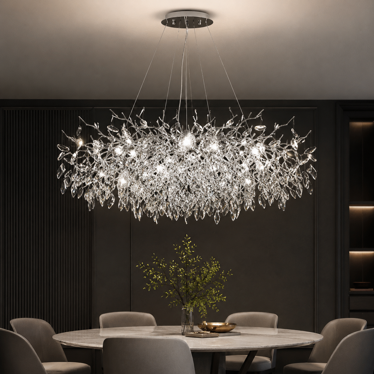 Modern chandelier hanging above a dining table in a dimly lit room.