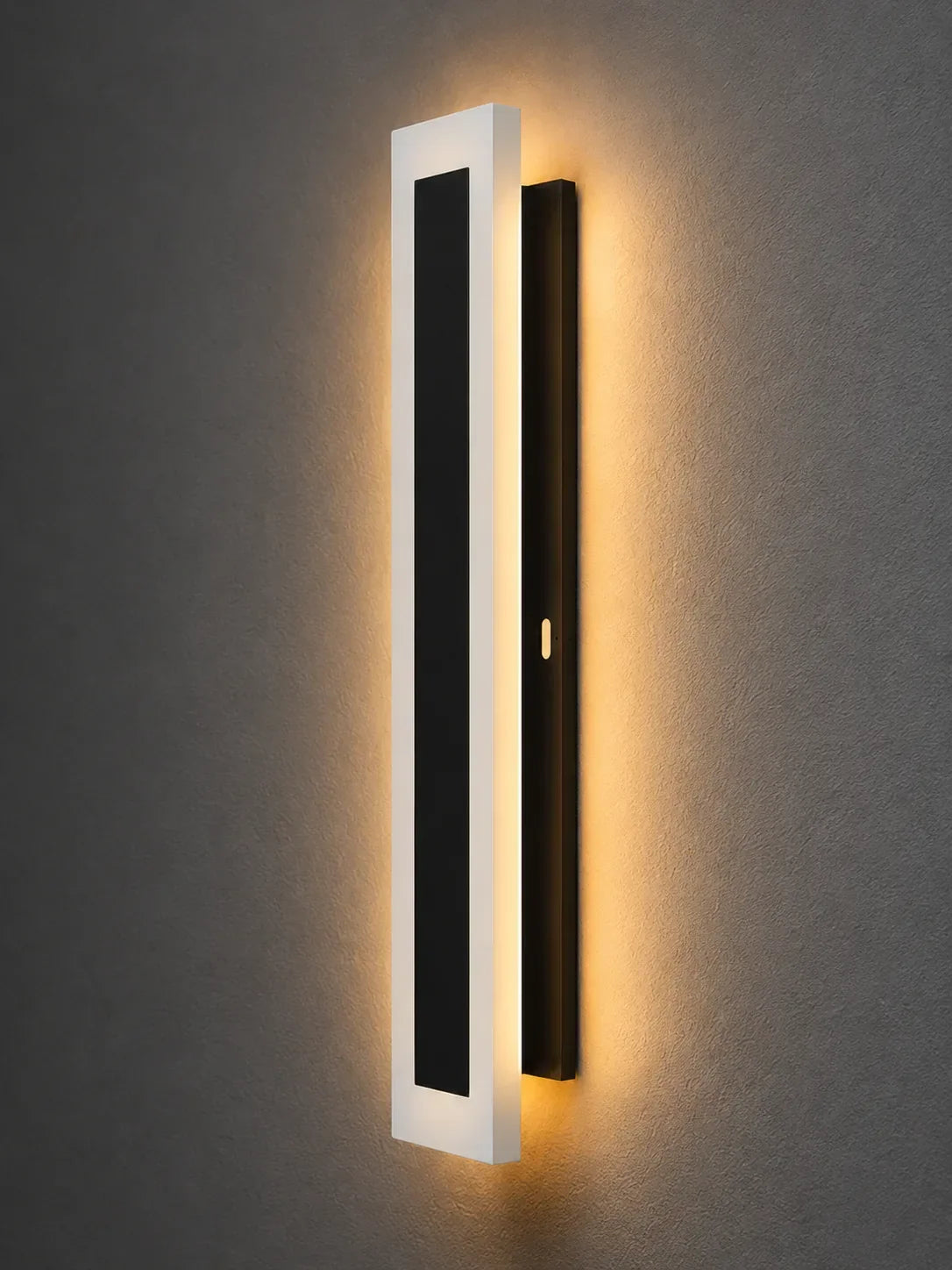 Modern wall sconce with sleek white and black design, emitting warm ambient light for contemporary interiors